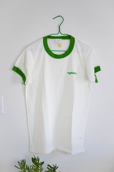 White t-shirt with green trim on a hanger against a white background