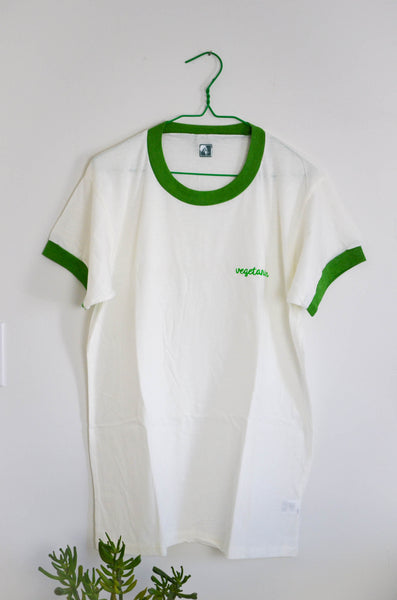 White t-shirt with green accents on a hanger against a white background